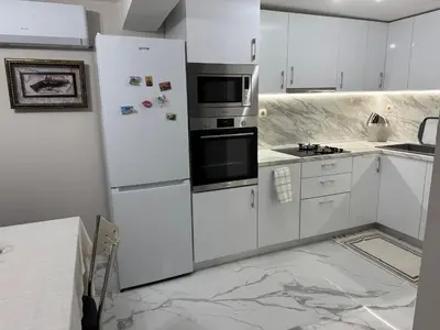 a kitchen with white cabinets and a refrigerator at Guest House Tatiana Studio in Petrich