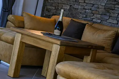a bottle of wine on a wooden table next to a couch at Къщи за гости Авена и Авена 2 in Banya