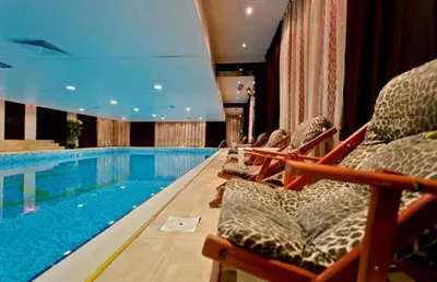 a swimming pool in a hotel with chairs next to it at Apartment Sam in Grand Monastery in Pamporovo