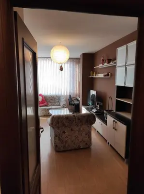 a living room with a couch and a table and a kitchen at Слънчев апартамент с прекрасна гледка, паркинг. in Smolyan