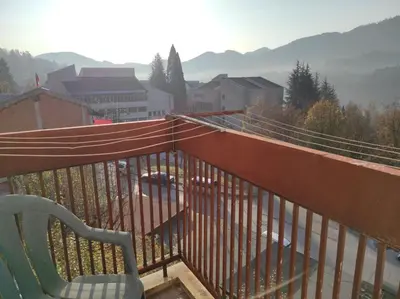 a chair on a balcony with a view of a city at Слънчев апартамент с прекрасна гледка, паркинг. in Smolyan