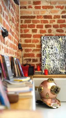 a table with books and a vase next to a brick wall at Modern and Spacious 3-Bedroom Entire House in Sofia