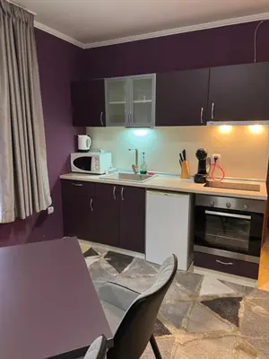 a kitchen with black cabinets and a table and chairs at Grand Monastery Apartment in Pamporovo