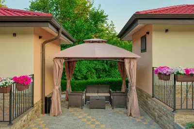 a large umbrella on a patio with chairs and flowers at Комплекс Колонада in Hisarya