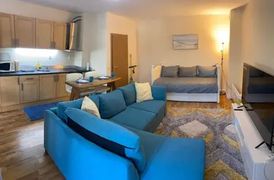 a living room with a blue couch and a kitchen at Ski to door at Mountain View 1BR condo Bansko in Bansko