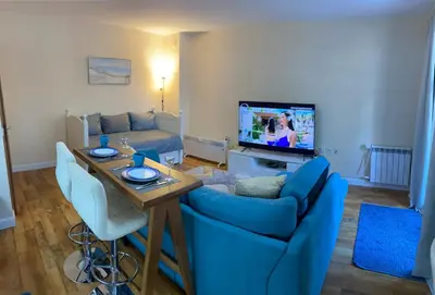a living room with a couch and a table and a tv at Ski to door at Mountain View 1BR condo Bansko in Bansko