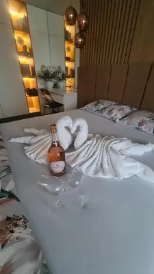 a bed with two towels and a bottle of alcohol at Апартамент Мегилукс 2 in Blagoevgrad
