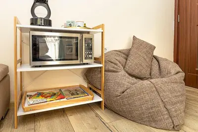 a microwave sitting on a shelf next to a chair at 2BR apartment ,10 minutes walk to TOP Center in Plovdiv