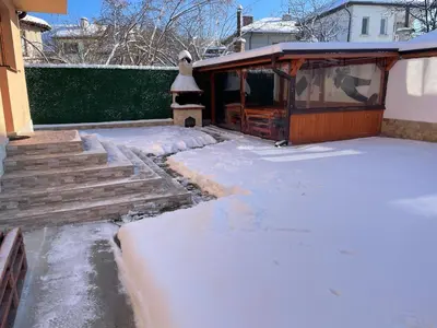 a yard covered in snow with stairs and a house at Villa Stoyanovata Kashta in Samokov