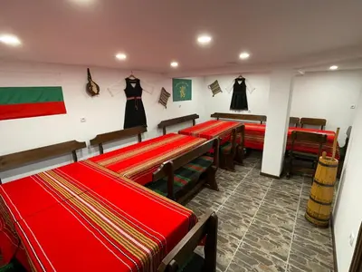 a room with red tables and chairs and black dresses on the wall at Villa Stoyanovata Kashta in Samokov