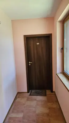 a hallway with a brown door and a window at Апартамент Николови Пампорово in Pamporovo
