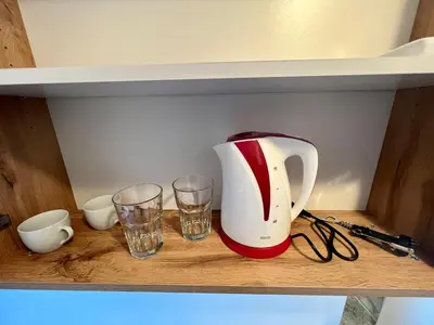 a tea kettle and two glasses on a shelf at The rainbow 2 in Sofia