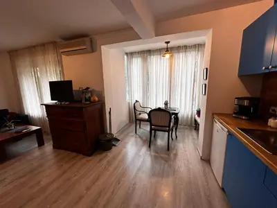 a living room with a table and a kitchen with a dining room at Eli's cozy place in Sofia
