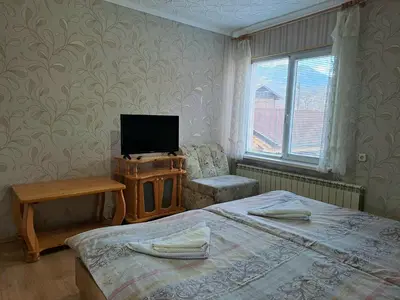 a bedroom with two beds and a tv and a chair at Kovacha Guest House in Raduil