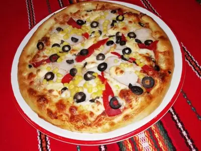 a pizza on a red plate on a table at Kovacha Guest House in Raduil