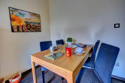 a wooden dining room table with blue chairs and a painting at 1BD Nest in the heart of a traditional Sofia by Flat Mаnager in Sofia