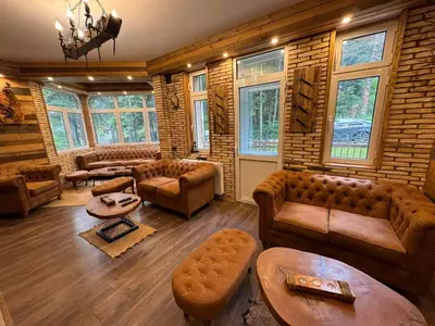 a living room with couches and tables and windows at The Forest Villa Borovets by BookVillaBG in Borovets