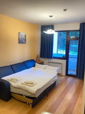 a bedroom with a bed and a blue couch at HQ Apartment Flora Violet in Borovets