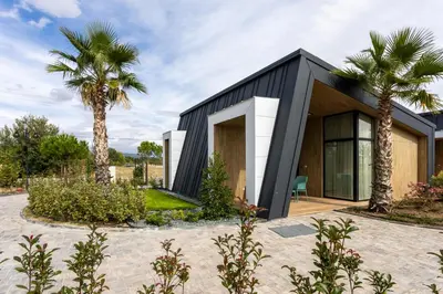 a black house with palm trees in front of it at Terme di Hissar Village in Hisarya