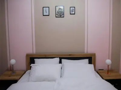 a bedroom with a bed with white sheets and pictures on the wall at Altavista mountain apartment in Samokov