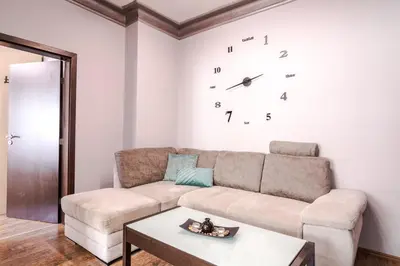 a living room with a couch and a clock on the wall at Your home away from home in Sofia