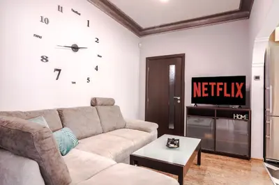 a living room with a couch and a clock on the wall at Your home away from home in Sofia