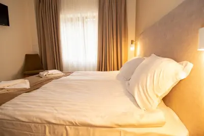 a bedroom with a large bed with white sheets and pillows at Hotel Alpinist, Malyovitsa in Govedartsi