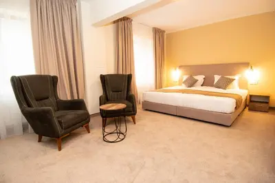 a hotel room with a bed and two chairs at Hotel Alpinist, Malyovitsa in Govedartsi