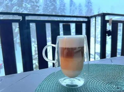 a glass cup of coffee sitting on a table at Arboro Borovets Gardens E43 in Borovets