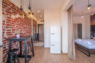 a room with a brick wall and a refrigerator and a table at Budget Stay in City Center near NDK in Sofia