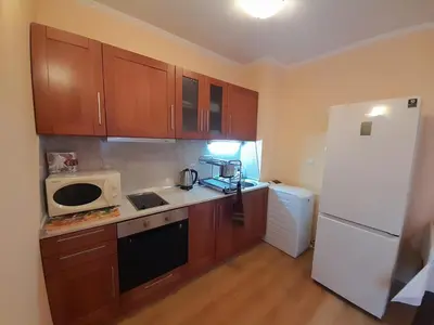 a kitchen with wooden cabinets and a white refrigerator at SNOW PEAK TODORKA APARTAMENT /NEXT TO THE LIFT/ 6 PERSONS in Bansko