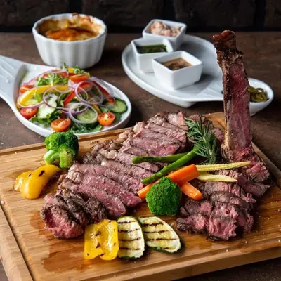 a cutting board with meat and vegetables on a table at SNOW PEAK TODORKA APARTAMENT /NEXT TO THE LIFT/ 6 PERSONS in Bansko
