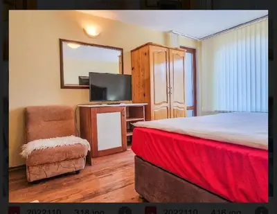a bedroom with a bed and a tv and a chair at Къща за гости Карасански in Bansko