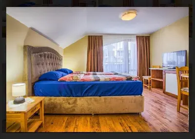 a bedroom with a bed with a blue comforter at Къща за гости Карасански in Bansko