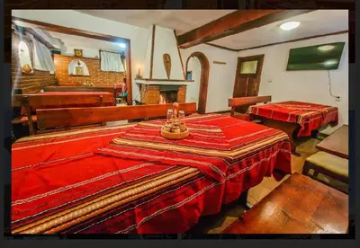 a living room with two tables with red blankets at Къща за гости Карасански in Bansko