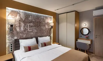 a hotel room with a bed and a wall at City Park Inn Apartment Cortona in Plovdiv
