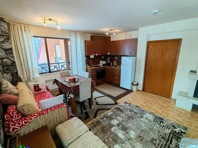 a living room with a couch and a table and a kitchen at Apartment Love Pamporovo in Pamporovo