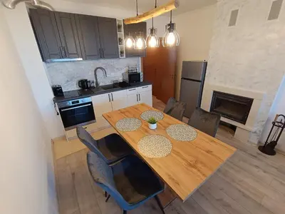 a kitchen with a wooden table and chairs in a kitchen at Viva 4 Apartment ski to the door complex Grand Monastery Pamporovo in Pamporovo