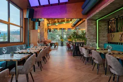 a dining room with tables and chairs and windows at 103 View Park Hotel in Panichishte