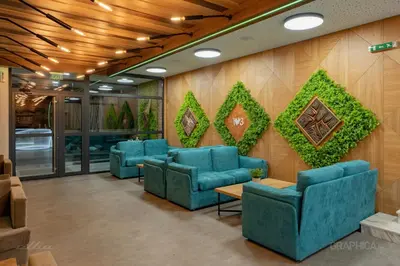 a waiting room with blue chairs and ivy on the wall at 103 View Park Hotel in Panichishte