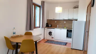 a kitchen with a table and a white refrigerator at Semiramida Garden Apartment 12 in Borovets
