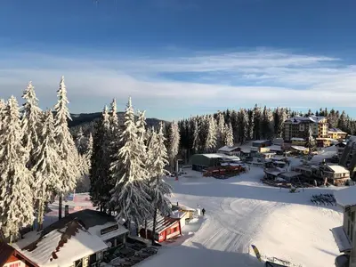 a ski resort with snow covered trees and buildings at Апартамент в хотел Стената, Пампорово in Smolyan