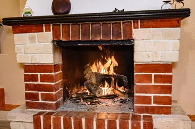 a brick fireplace with a fire in it at Lalev Guest House in Bansko