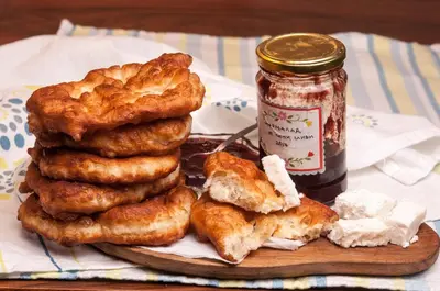 a pile of food on a cutting board with a jar of jam at Lalev Guest House in Bansko