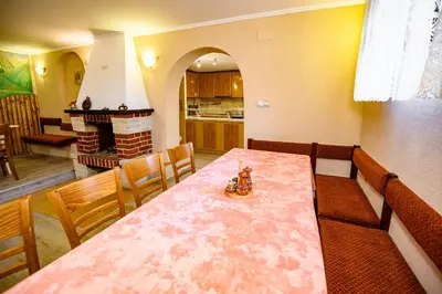 a dining room with a table and a kitchen at Lalev Guest House in Bansko