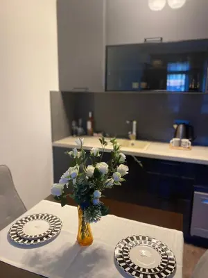 a vase of flowers on a table with two plates at Studio Nr 6 in Bansko