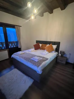 a bedroom with a bed and a large window at Vladimirov's House Kovachevitsa , Цяла къща in Kovachevitsa