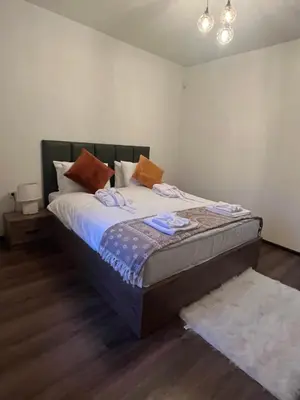 a bedroom with a large bed with white sheets at Vladimirov's House Kovachevitsa , Цяла къща in Kovachevitsa