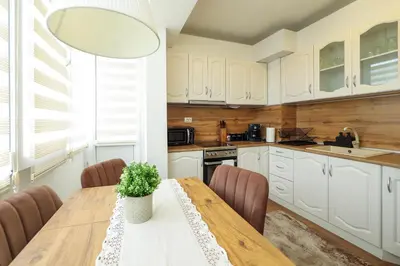 a kitchen with white cabinets and a wooden table at Central Apartment near the Park in Gotse Delchev
