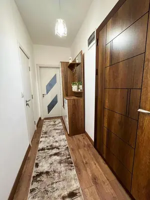 a hallway with a large wooden door and a rug at Central Apartment near the Park in Gotse Delchev